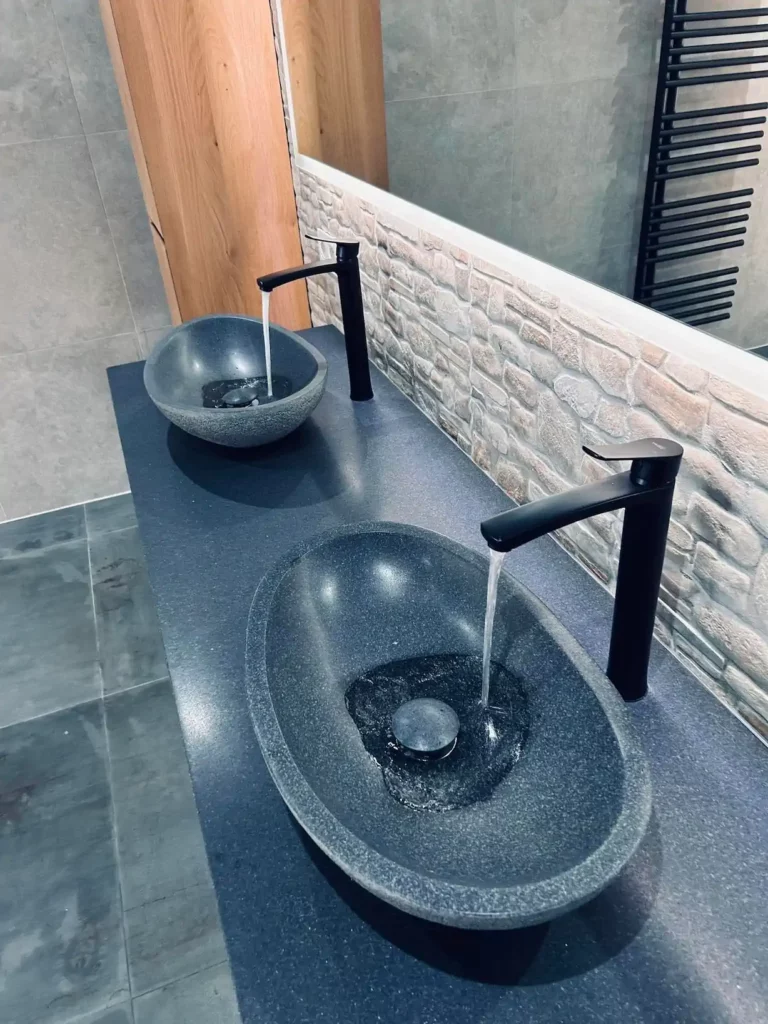 Double vasque en pierre naturelle avec robinetterie noire, intégrée dans une salle de bain contemporaine