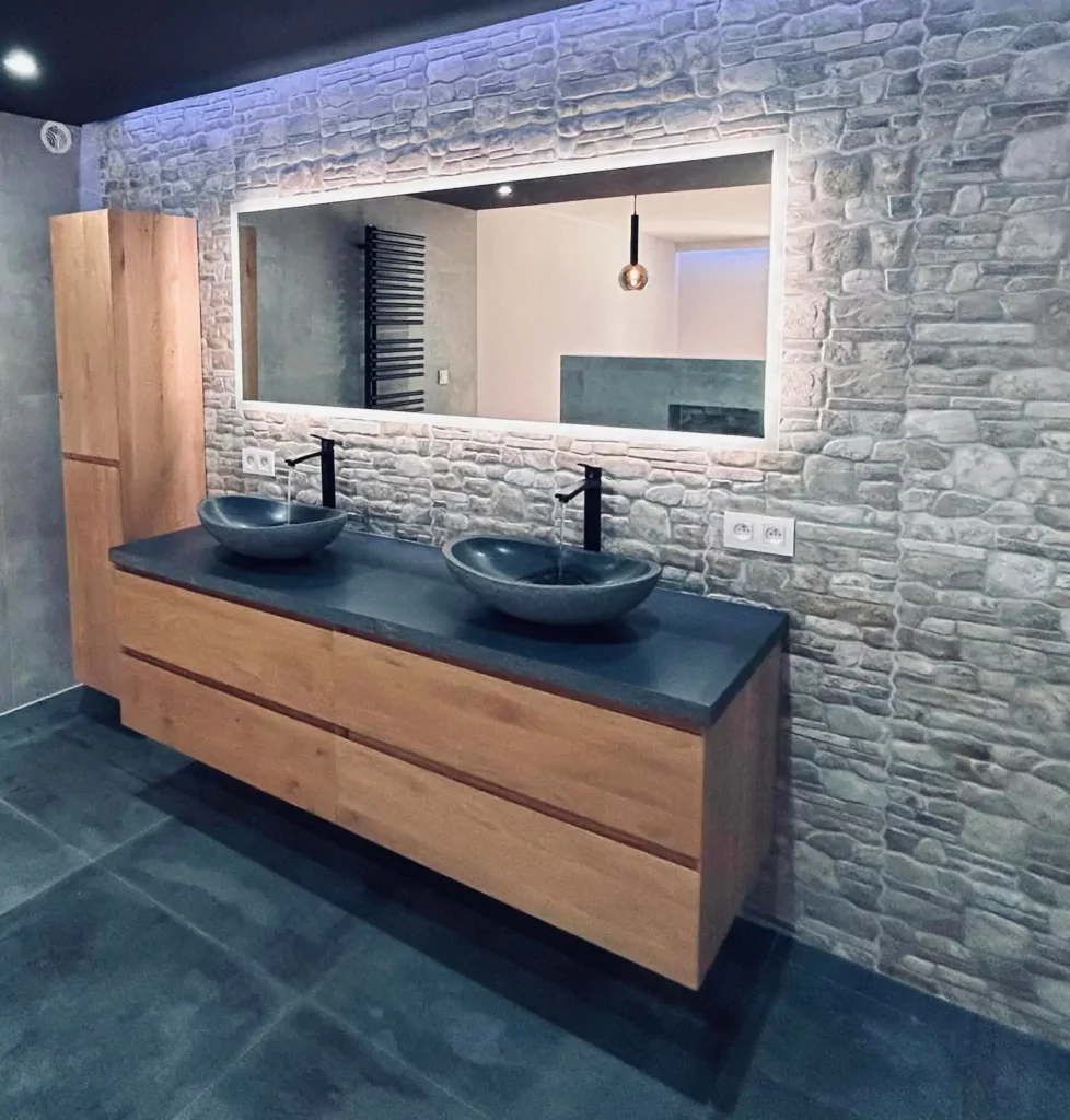 Salle de bain contemporaine rénovée à Baelen avec meuble suspendu en bois, double vasque et mur en pierre
