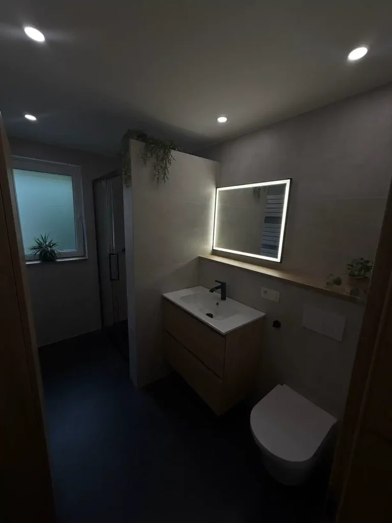 Vue d'une salle de bain rénovée à Jalhay : au premier plan, un meuble vasque en bois clair avec mitigeur noir