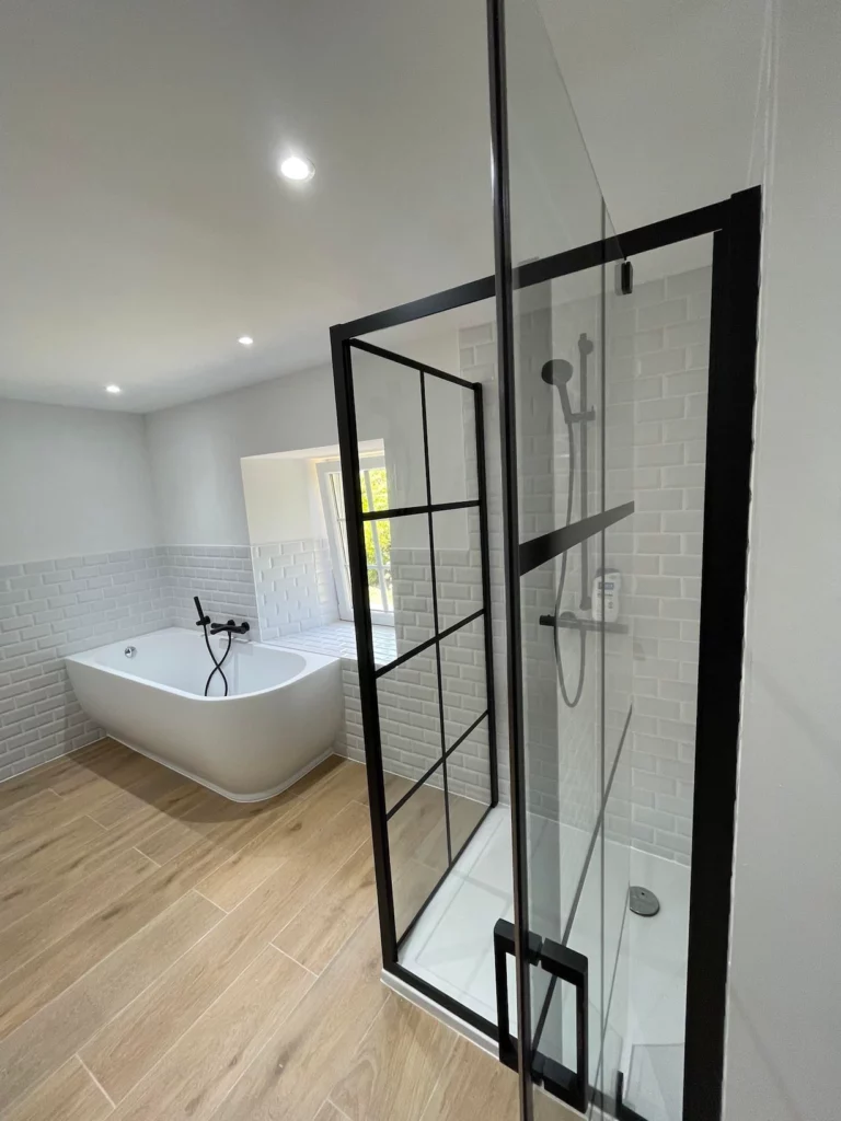 Douche vitrée style atelier et baignoire îlot dans une salle de bain rénovée à Saint-Vith