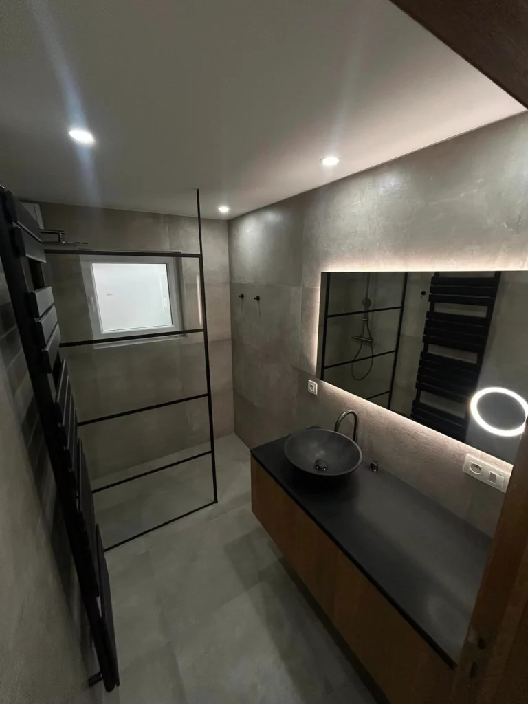 Vue d’ensemble d’une salle de bain contemporaine rénovée à Welkenraedt avec douche verrière noire et meuble