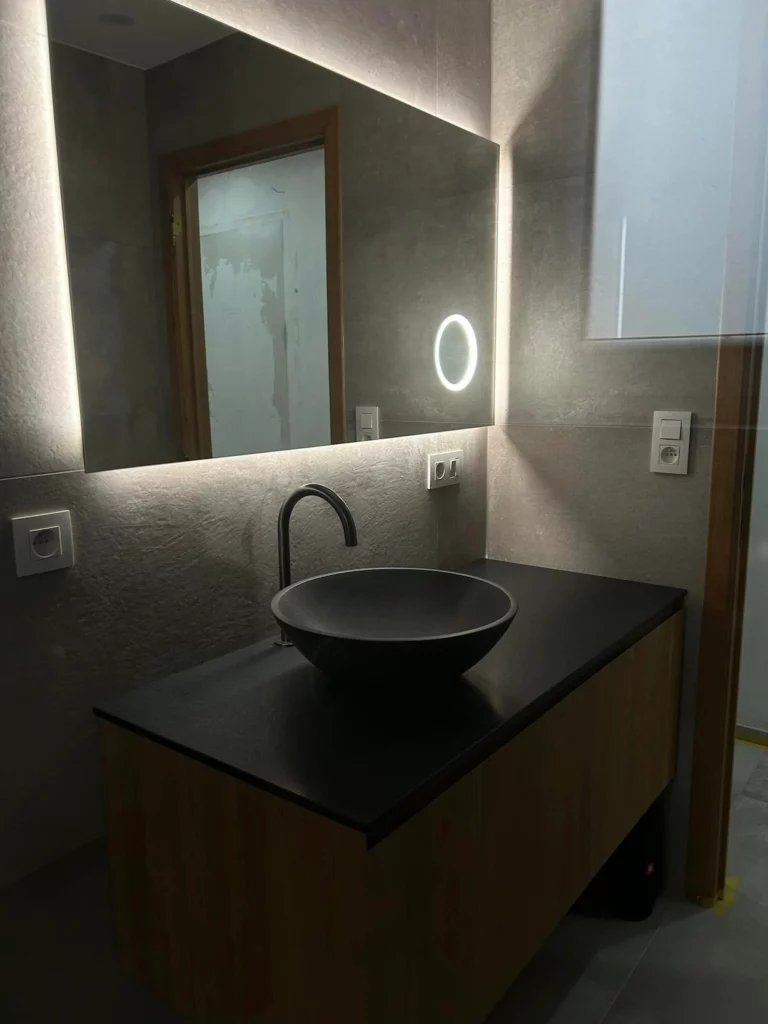 Meuble vasque en bois avec vasque noire et miroir rétro-éclairé LED dans une salle de bain contemporaine à