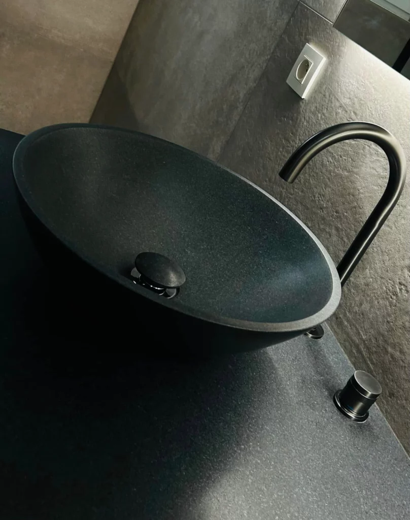 Détail de la vasque noire avec robinetterie assortie, intégrée dans une salle de bain contemporaine à